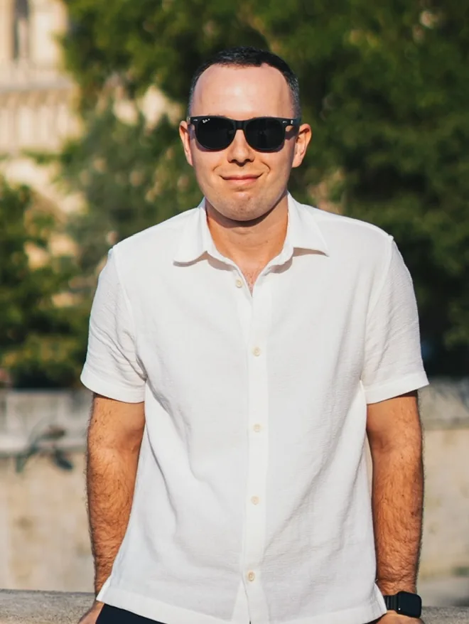 Krzysztof Dąbrowski, smiling, in a white shirt outdoors.